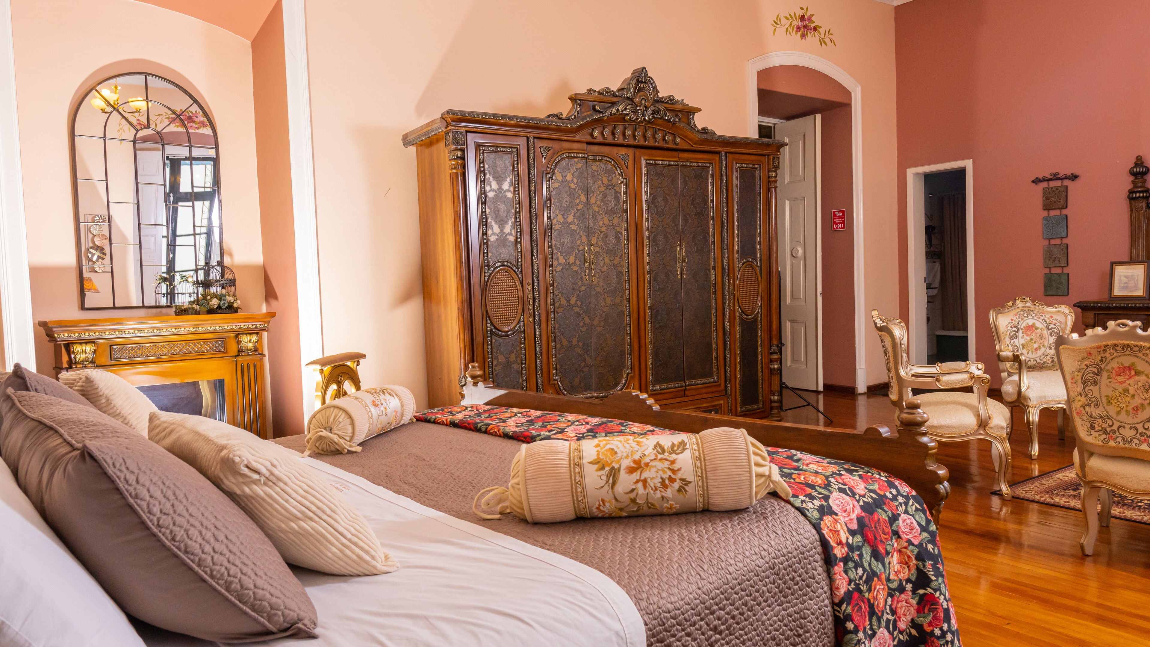 Un dormitorio con una cama grande, un armario de madera y dos sillas.