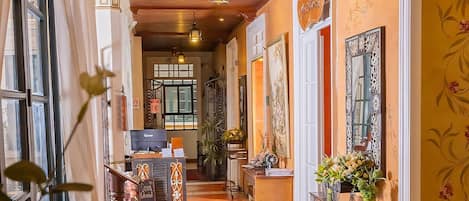 A hallway with wooden ceiling, a reception desk, and a sign that reads "Casa Colonial".