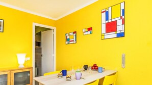A bright yellow room with a wooden table and yellow chairs, a white lamp, and a door leading to another room. - Nice apartment for 4 people with WIFI, TV and terrace (Calonge)