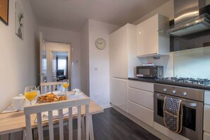 A modern kitchen with white cabinets, a stainless steel stove, and a microwave.