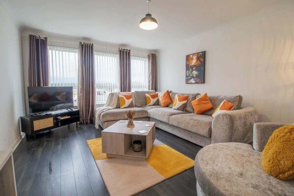 A modern living room with a grey sofa, a coffee table, and a television.