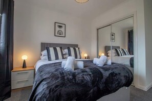 A bedroom with a bed, bedside lamps, a mirror, and a nightstand.