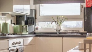 A kitchen with a window, a sink, and a dining area with a table and chairs.
