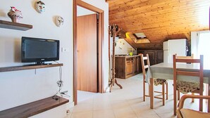 Une pièce chaleureuse, meublée en bois, avec une télévision, une table à manger et des chaises.