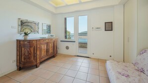 Ein Zimmer mit Holzschrank, einer Couch, einer Decke mit Dachfenstern und einer zur Außenseite führenden Tür.