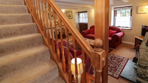 A staircase with wooden balusters leading to a living room with a red sofa, a coffee table, and a rug.