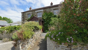 A stone building with a small porch and a garden with flowering plants.