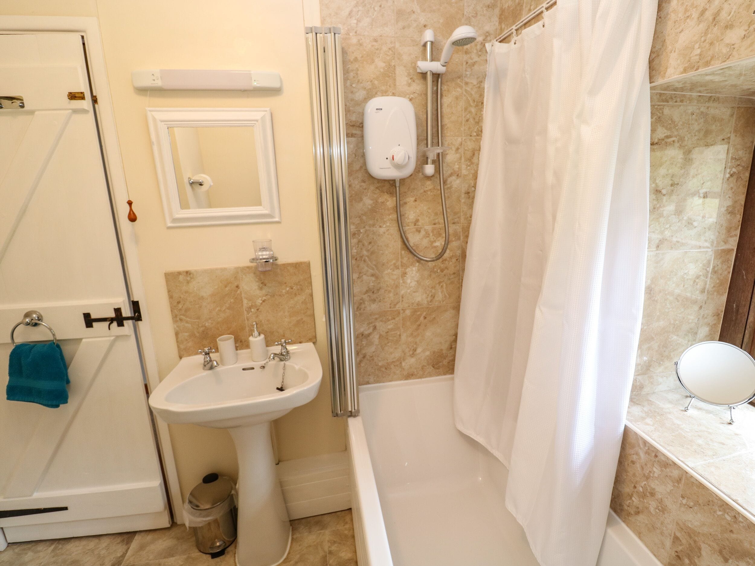 A bathroom with a bathtub, a sink, a shower, and a mirror.