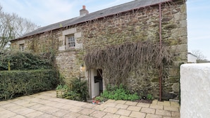 A stone building with a tiled patio and a small entrance.