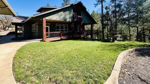 A two-story lodge with a stone facade, a covered porch, and a stone fireplace.