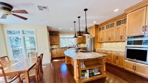 A modern kitchen with wooden cabinets, a granite countertop island, and stainless steel appliances.