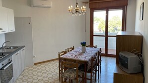 Una cocina compacta con una mesa de comedor, sillas, una araña y un televisor.