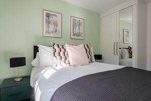 Ein Schlafzimmer mit einem Bett, zwei Nachttischen, einem Kleiderschrank und zwei gerahmten Bildern an der Wand.