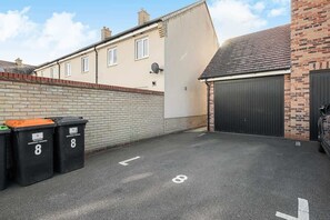 Un espace de stationnement avec des places délimitées, un mur en briques et une porte de garage.