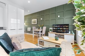Una sala de estar moderna con un sofá, una mesa de centro y un televisor mostrando una videollamada.