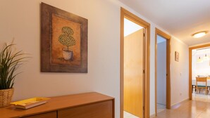 Ein Flur mit einem Holzschrank, einer Topfpflanze und einem Baumgemälde.