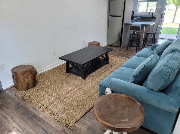 A living room with a blue sofa, a wooden coffee table, and two wooden stools. - 2 Bedroom Cabin Across Lake Simcoe (Innisfil)