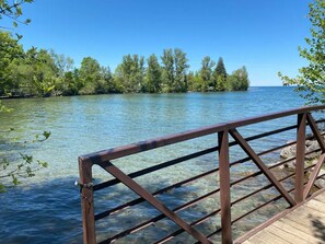 Une jetée en bois s’étendant dans un lac aux eaux limpides, entouré d’arbres.