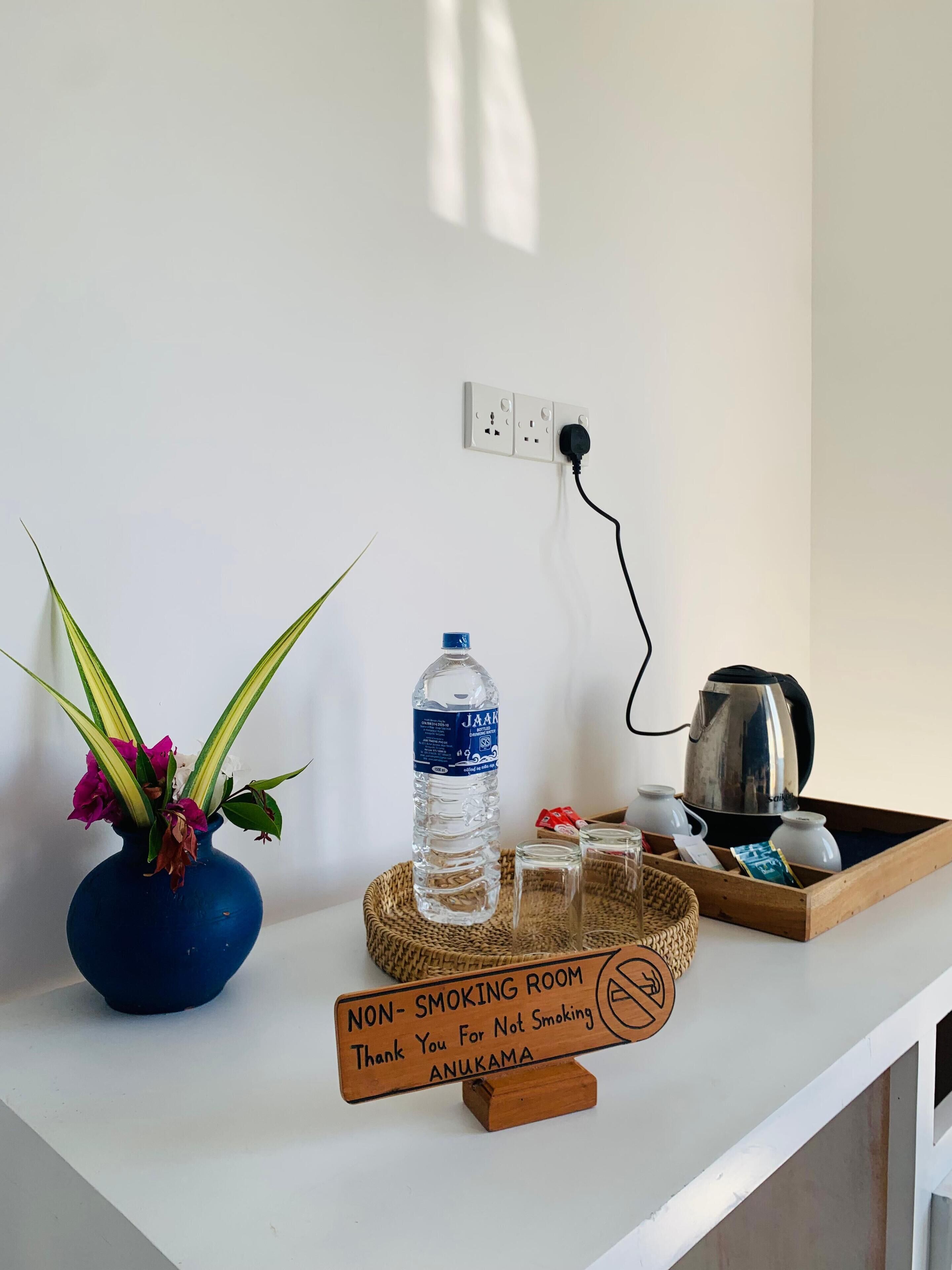 A non-smoking room with a water bottle, a kettle, a tray with glasses, and a thank you sign.