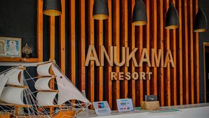 A reception desk at Anukama Resort with a wooden backdrop, hanging pendant lights, and a model ship. - Anukama Resort  (Nilaveli)