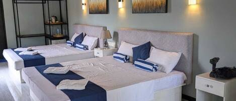 A hotel room with two beds, a nightstand, a lamp, and artwork on the walls.