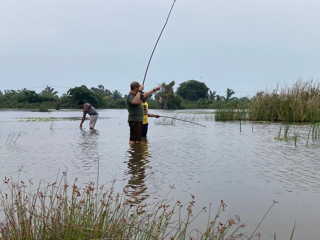 Dos personas pescan en una zona inundada, con el agua a la altura de la cintura.