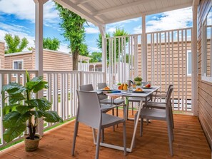 An outdoor patio with a table and chairs, surrounded by white railings and wooden deck flooring.