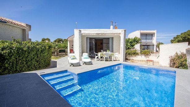 Une piscine avec des marches permettant d’y accéder, entourée d’un patio aménagé avec du mobilier d’extérieur.
