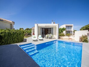 A swimming pool with steps leading into it, surrounded by a patio area with outdoor furniture.