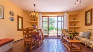 Un salon chaleureux avec un coin repas, de grandes fenêtres et un sol à motifs.