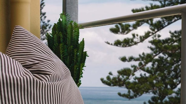 Un canapé à rayures donnant sur la mer et les arbres.