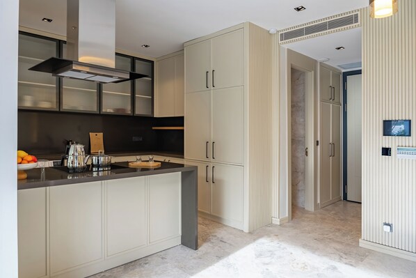 A modern kitchen with a central island, built-in cabinets, and a stainless steel range hood.
