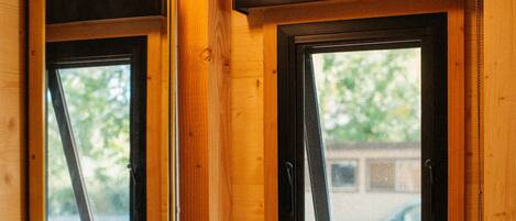 Un baño de cabaña de madera con un lavamanos blanco, un espejo y una ventana sobre el lavamanos.