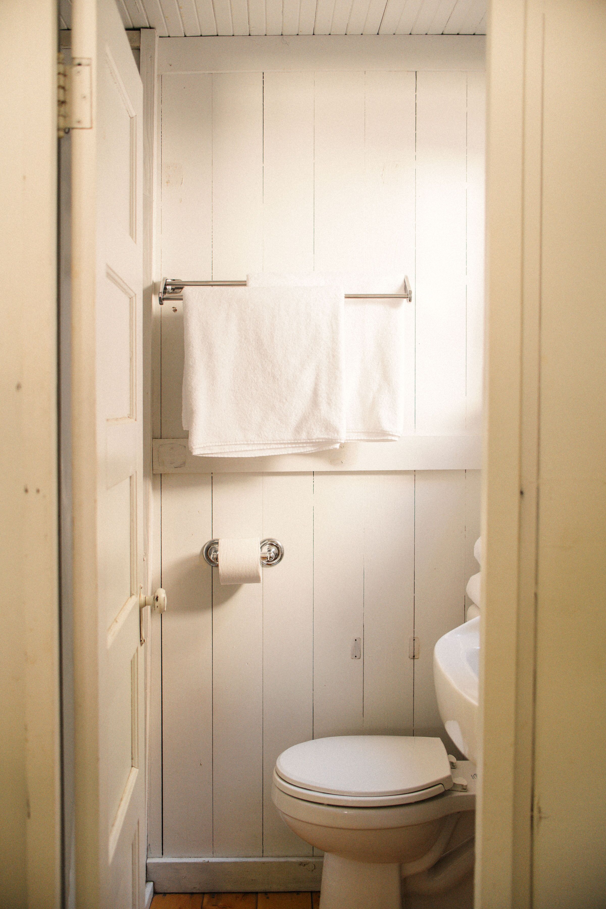 A small, white bathroom with a toilet, a towel rack, and a toilet paper holder.