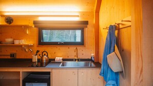 Una cocina compacta con un lavamanos, una ventana y armarios de madera.