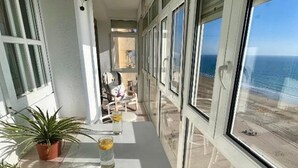 Ein Balkon mit Blick auf den Ozean, Blumentöpfen und einem Tisch mit Gläsern.