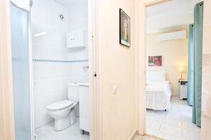 A bathroom with a toilet, a shower, and a sink.