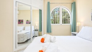 Une chambre d’hôtel avec un lit, une fenêtre avec des rideaux, une table de chevet avec une lampe et un miroir.