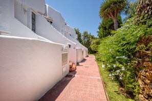 A pathway leading to a row of white buildings with a brick walkway.
