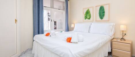 Une chambre à coucher bien rangée, avec un grand lit, une table de chevet et une commode.