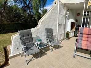 An outdoor patio area with two wicker chairs, a small table, and a potted plant. - L14 Jardines Fase 1 - Apartment (Sitio de Calahonda)