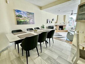 Un espace repas avec une longue table, des chaises noires et un tableau accroché au mur.