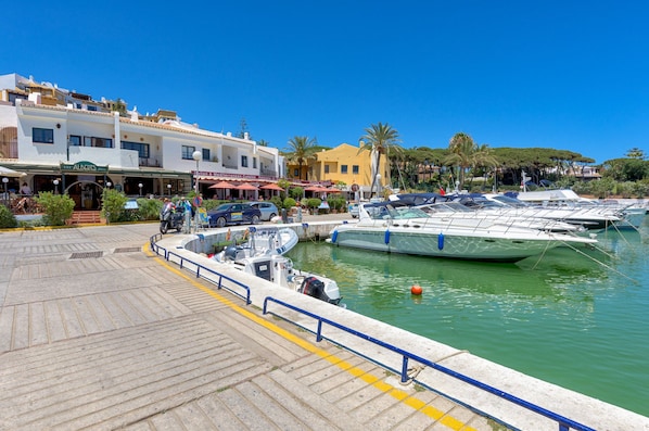 Een jachthaven met verschillende boten aanmeren, een verharde promenade en een restaurant genaamd 'Albert's Grill' met terras.