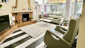 Un salon avec une cheminée, un canapé, un fauteuil et un téléviseur.
