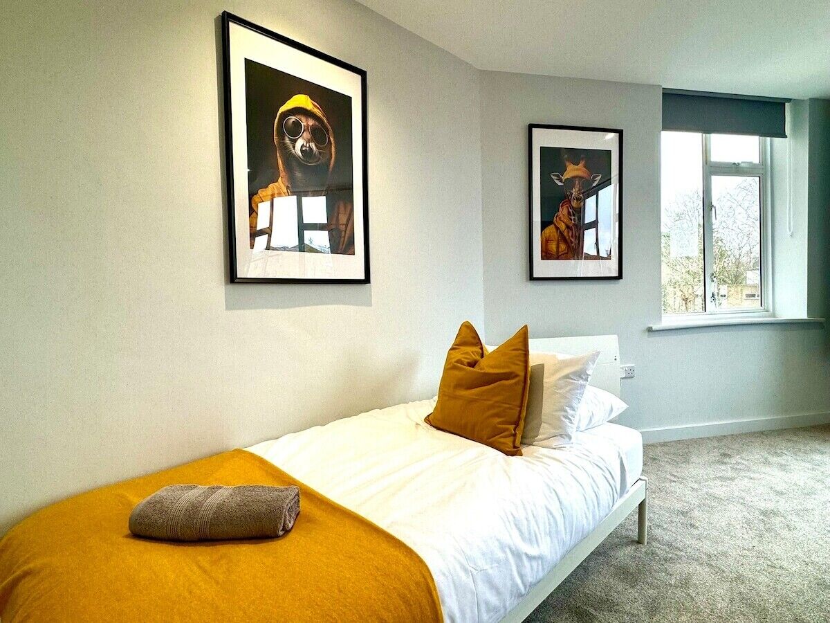 Un dormitorio con una cama, una ventana y dos cuadros en la pared.