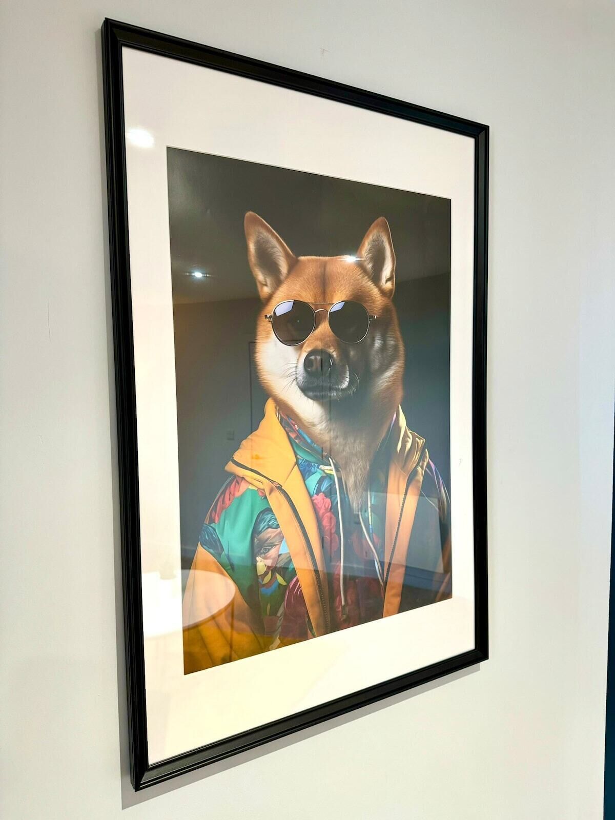 A framed picture of a dog wearing sunglasses and a colorful jacket.