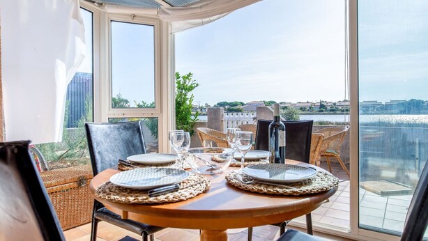 A dining table set for four with a view of a body of water and distant buildings. - Cosy apartment for 4 guests with WIFI, TV and terrace (Narbonne)