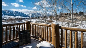 Eine Holzterrasse mit Blick auf schneebedeckte Berge und einen klaren Himmel.
