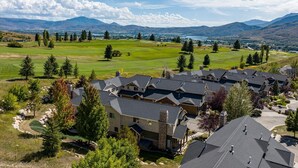 Ein Wohngebiet mit mehreren Häusern, einem Golfplatz und Bergen im Hintergrund.