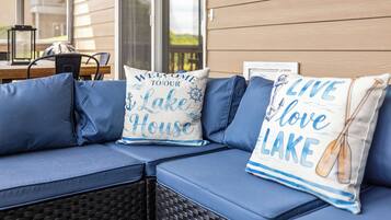 A blue sofa with cushions, a wicker chair, and a table with a lantern.